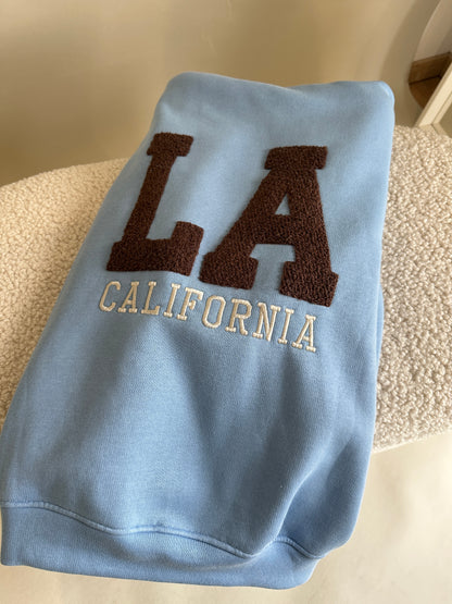 Pullover mit Kapuze in Hellblau mit Aufschrift in Schokobraun LA